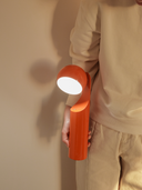 Person holding a red flashlight against a plain background