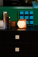 Small lamp on a dark surface with books and a colorful shelf in the background
