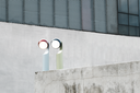 Two round lights on a concrete wall with a modern building in the background