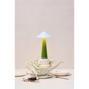 Tipsy table lamp in green glowing on a table at home